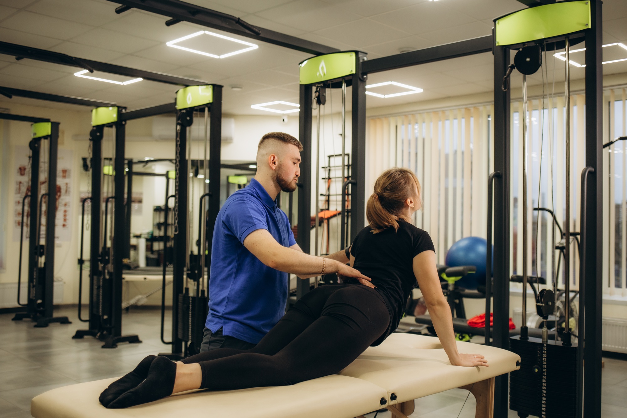 Side view of young female athlete doing back bending exercise during physiotherapy after sports